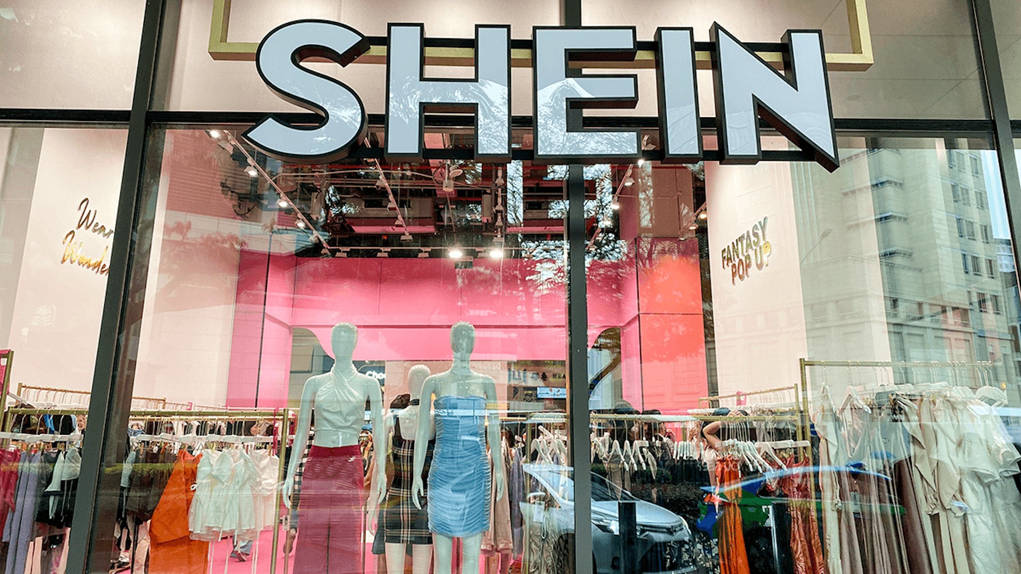 Front view of Shein store display in Paris showing mannequins and clothing racks inside the pink-themed boutique.