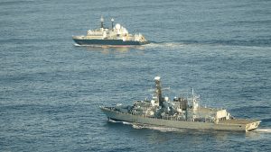 A Royal Navy warship escorts the Russian vessel Yantar in open waters, with both ships travelling side by side at sea.