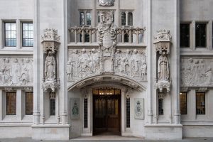 The main entrance of the UK Supreme Court featuring detailed stone carvings, statues, and gothic architectural elements.