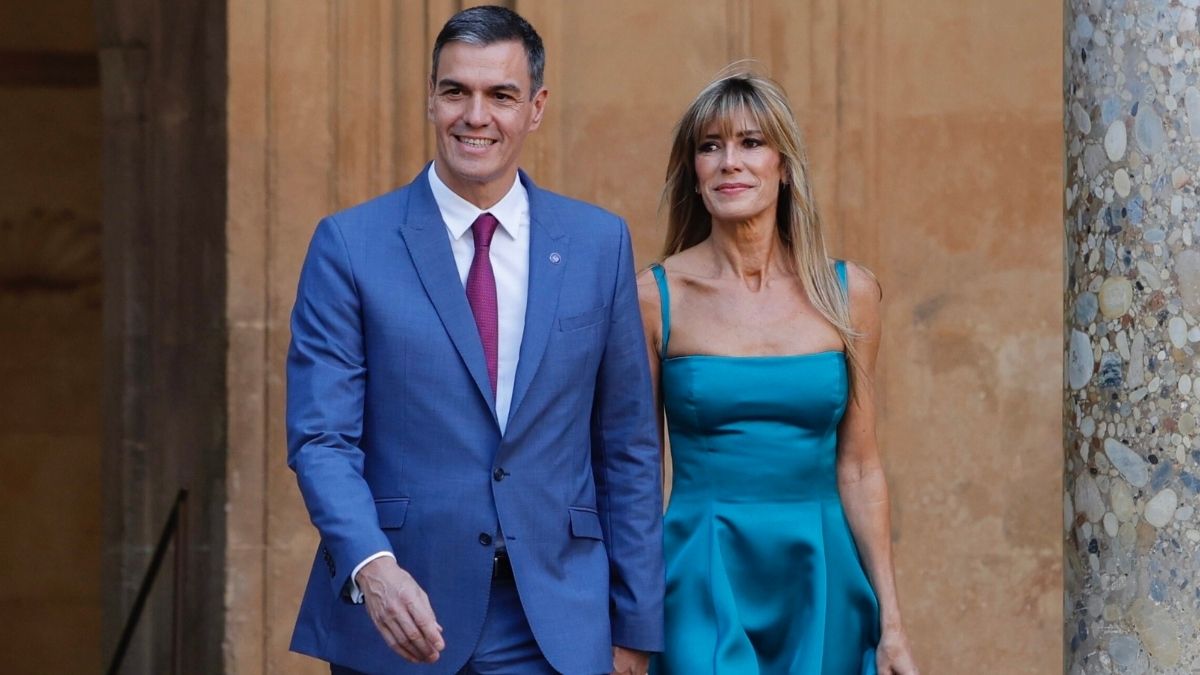 Pedro Sánchez and Begoña Gómez walking together while dressed formally at an outdoor event.