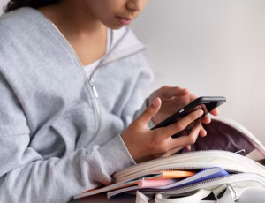 Teenager checking a smartphone before school, illustrating debate over under-16 social media use in the UK