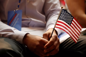 A person holding a small American flag during a U.S. naturalization or citizenship event.