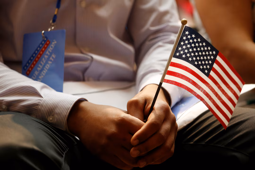 A person holding a small American flag during a U.S. naturalization or citizenship event.