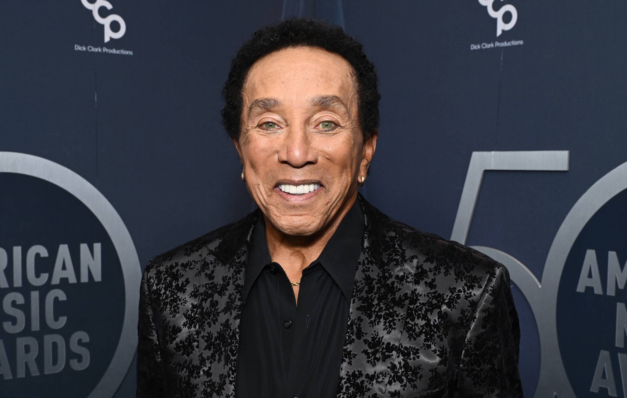Smokey Robinson smiling on the red carpet at the American Music Awards.