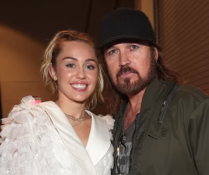 Billy Ray Cyrus and Miley Cyrus standing together and posing for a photo.