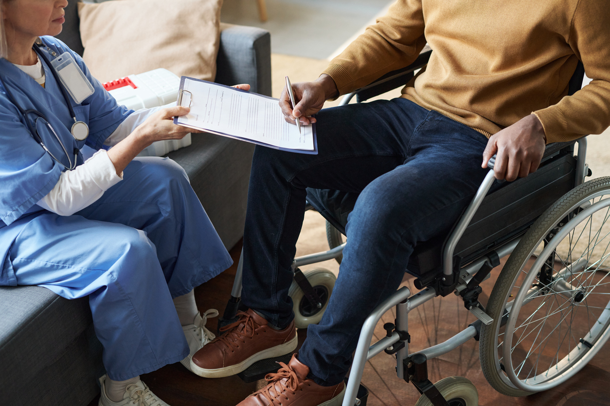 black man with disability using wheelchair and signing medical form