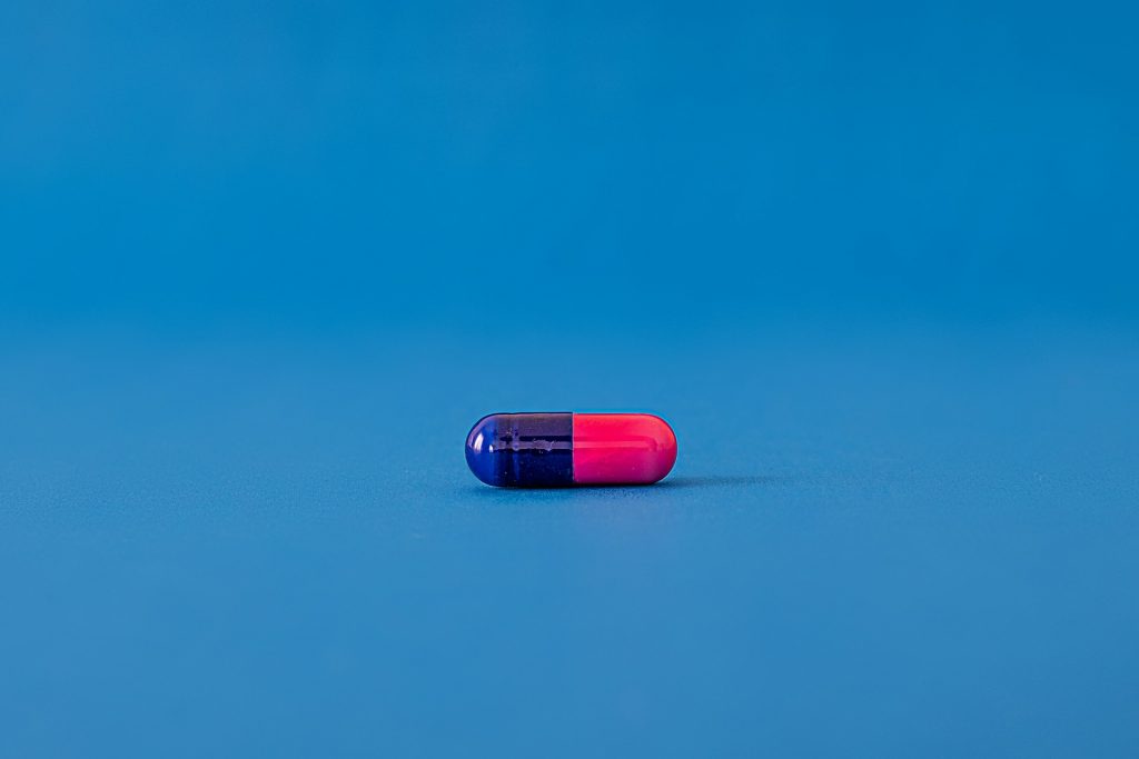 A pink and blue pill on a blue background.