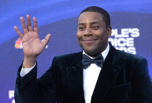 Kenan Thompson waves while attending a red carpet event in a black tuxedo