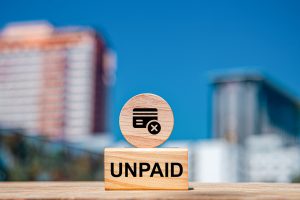 unpaid words on wooden blocks, unpaid business concept, city background